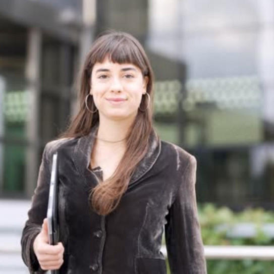 Frau mit Notebook im Arm vor modernem Gebäude mit Glaswänden