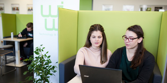 Zwei Studentinnen sitzen vor einem Laptop.