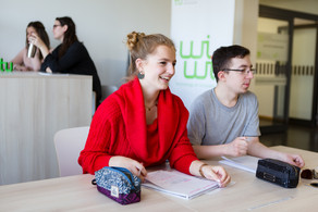 Vier Studierende, zwei im Vordergrund und zwei im Hintergrund, unterhalten sich.