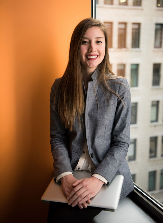Foto: Frau mit Laptop auf dem Schoß sitzt auf Fensterbank
