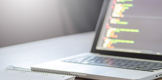 Laptop und Block Ein Laptop, ein Notizblock und ein Kugelschreiber liegen auf einem Tisch.