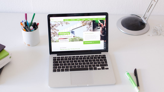 Arbeitsplatz mit Laptop Arbeitsplatz am Schreibtisch, mit eingeschaltetem Laptop und Stiften.