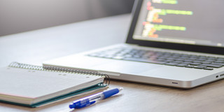 Arbeitsplatz mit Laptop und Notizen Foto eines Laptops und Notizbuches auf einem Schreibtisch.